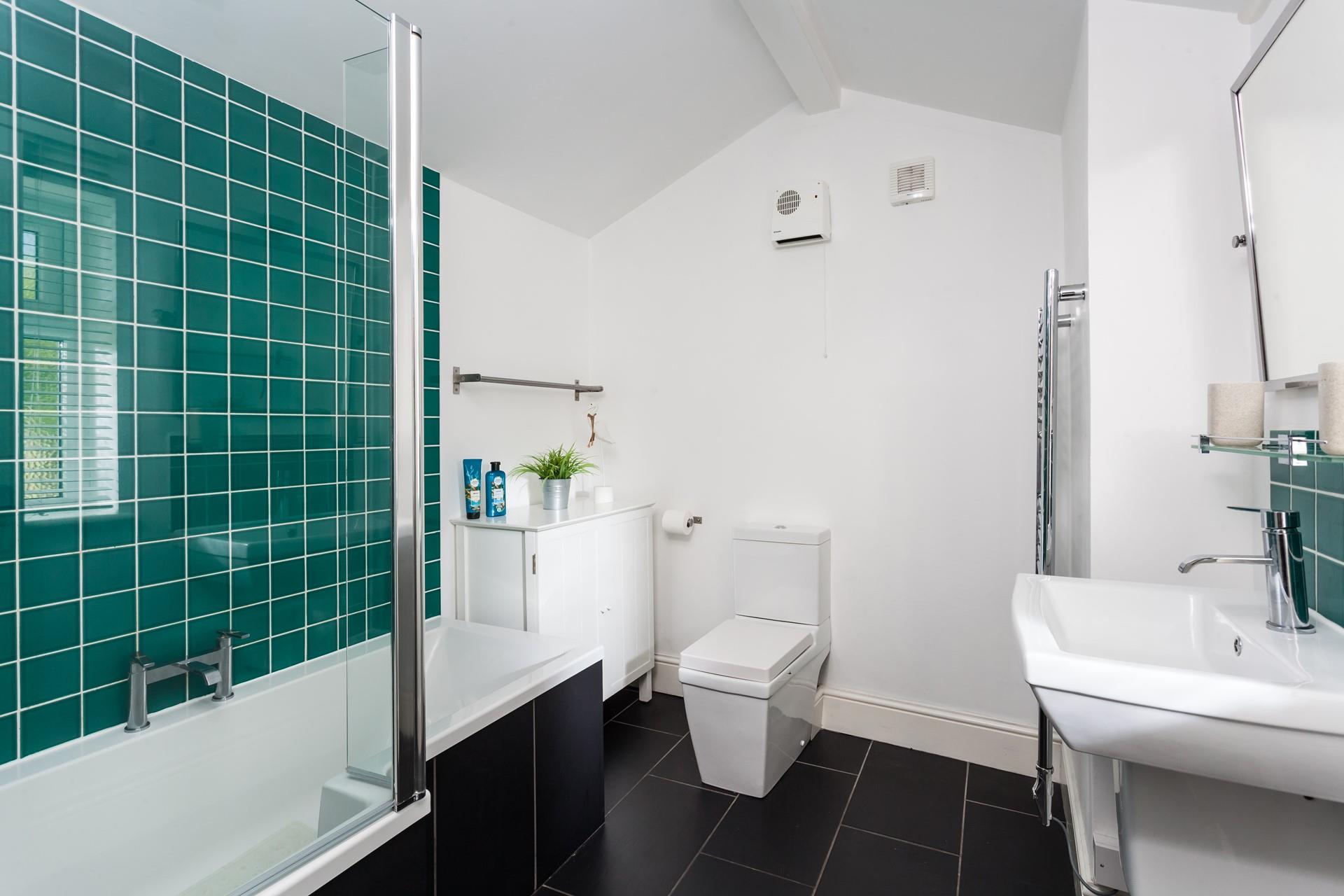The stylish bathroom has a bath with a shower over.