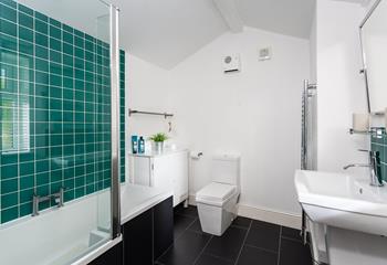 The stylish bathroom has a bath with a shower over.