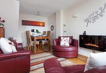 The comfortable sitting room has leather sofas and an electric-effect fire place.