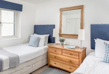 Bedroom 2 has twin beds and a wooden chest of drawers for ample storage space.
