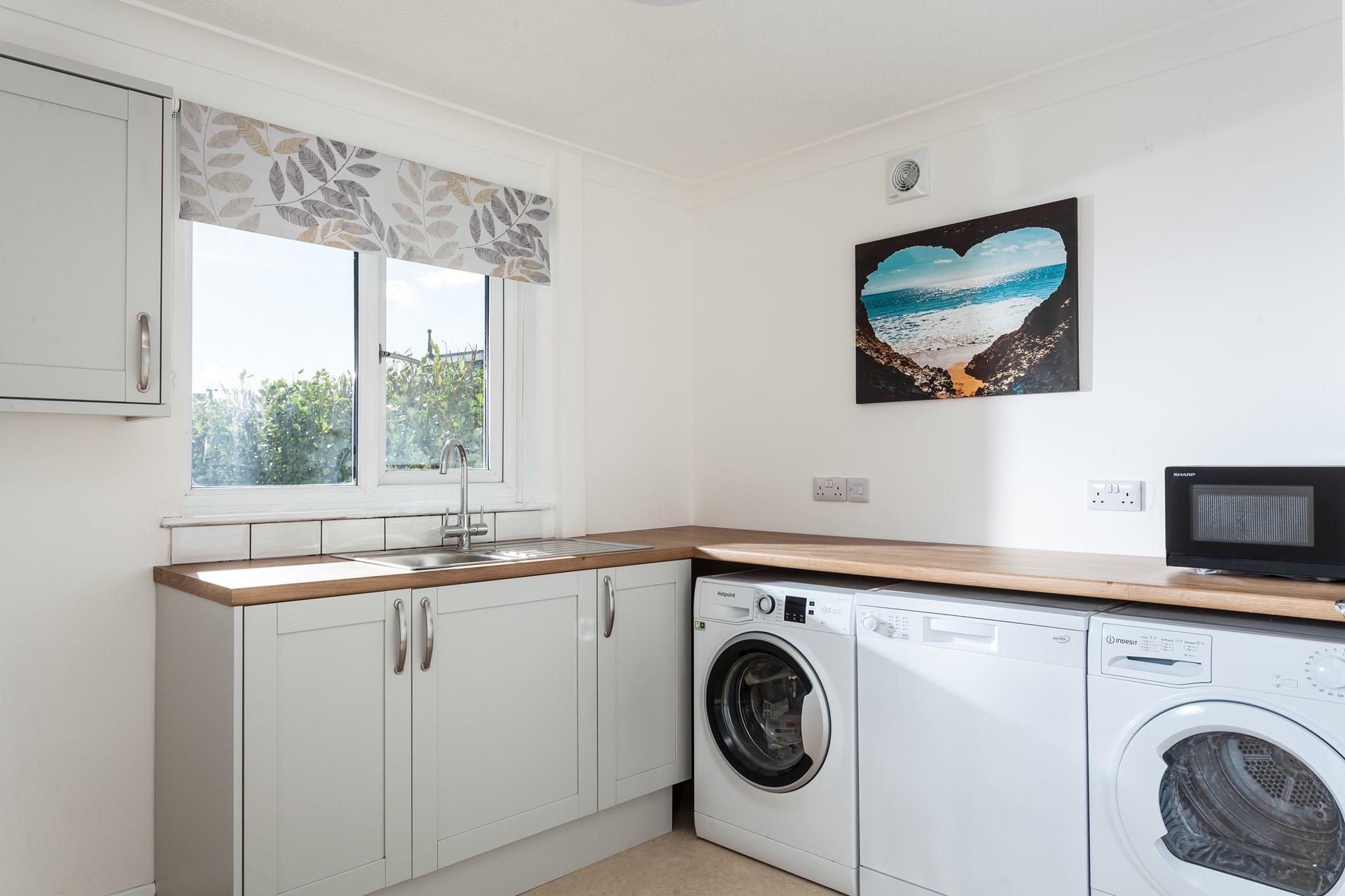 The utility room has handy appliances including a washing machine, tumble dryer and dishwasher.