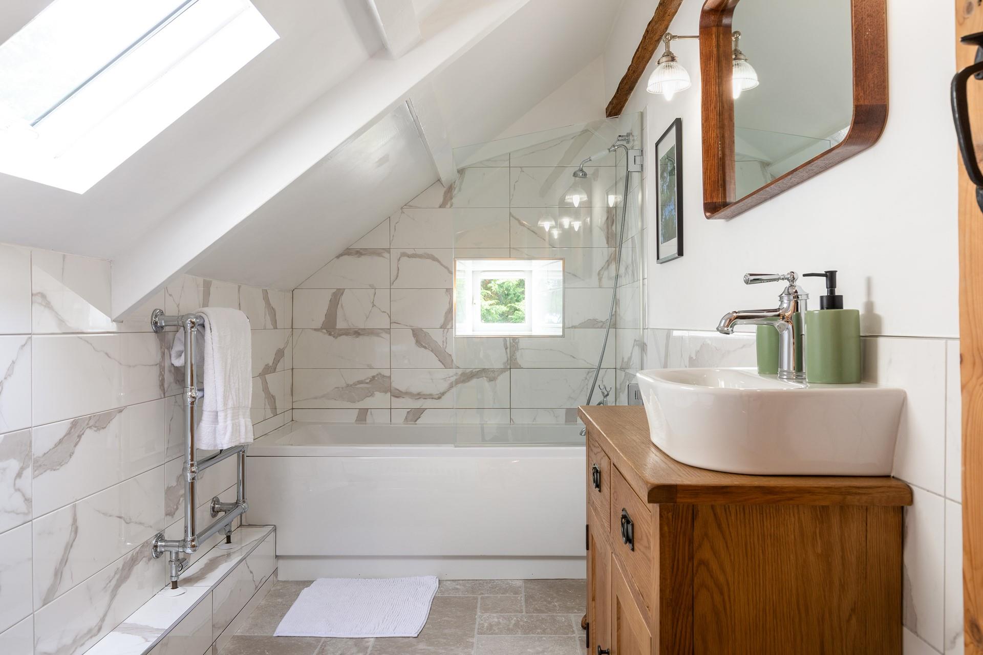 The family bathroom has stylish marble effect tiles and a heated towel rail.