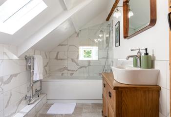 The family bathroom has stylish marble effect tiles and a heated towel rail for warm fluffy towels.