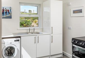 The utility room has a washing machine and plenty of extra storage space.