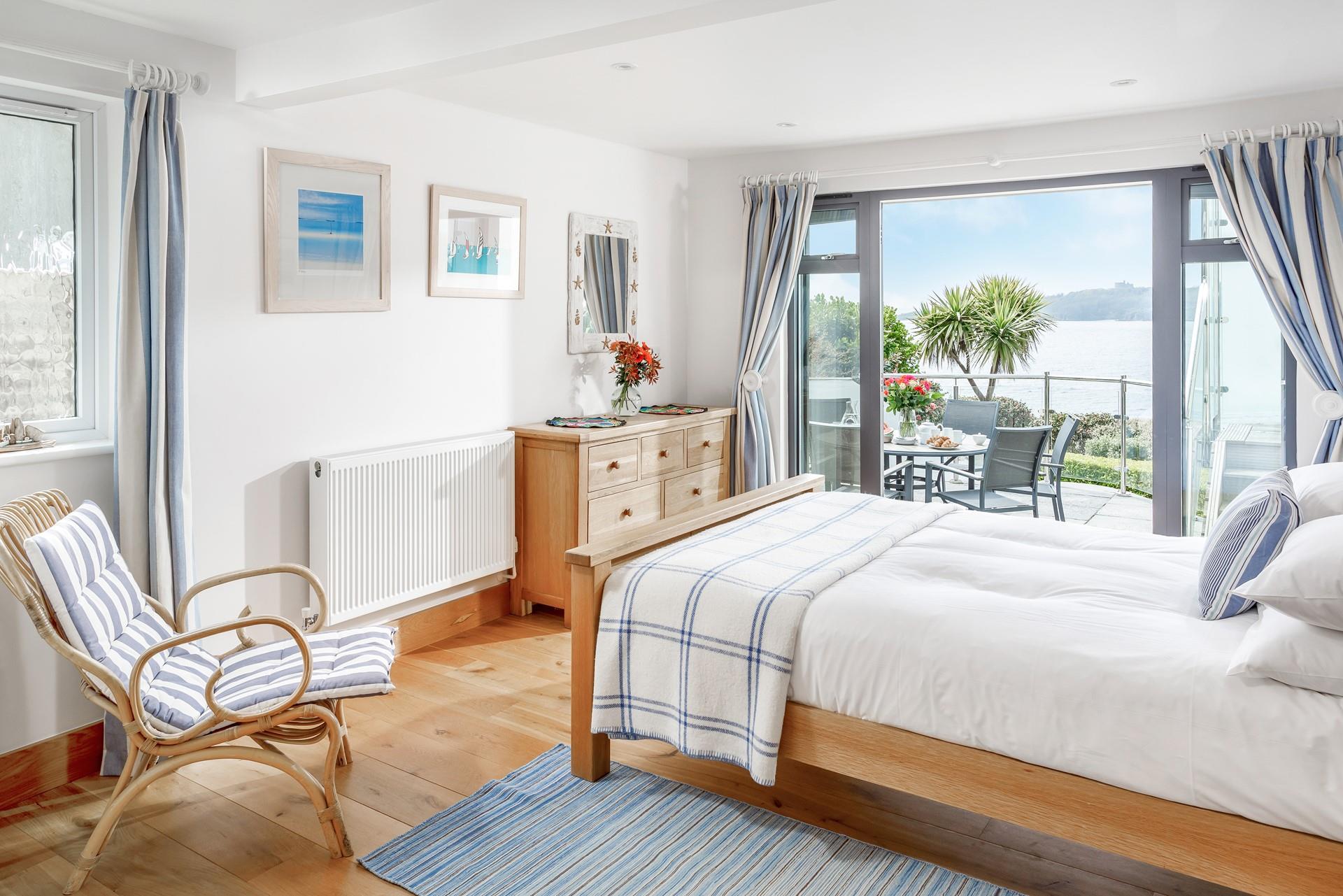 Charming bedroom 3 is decorated with whites and blues with doors out to a terrace.