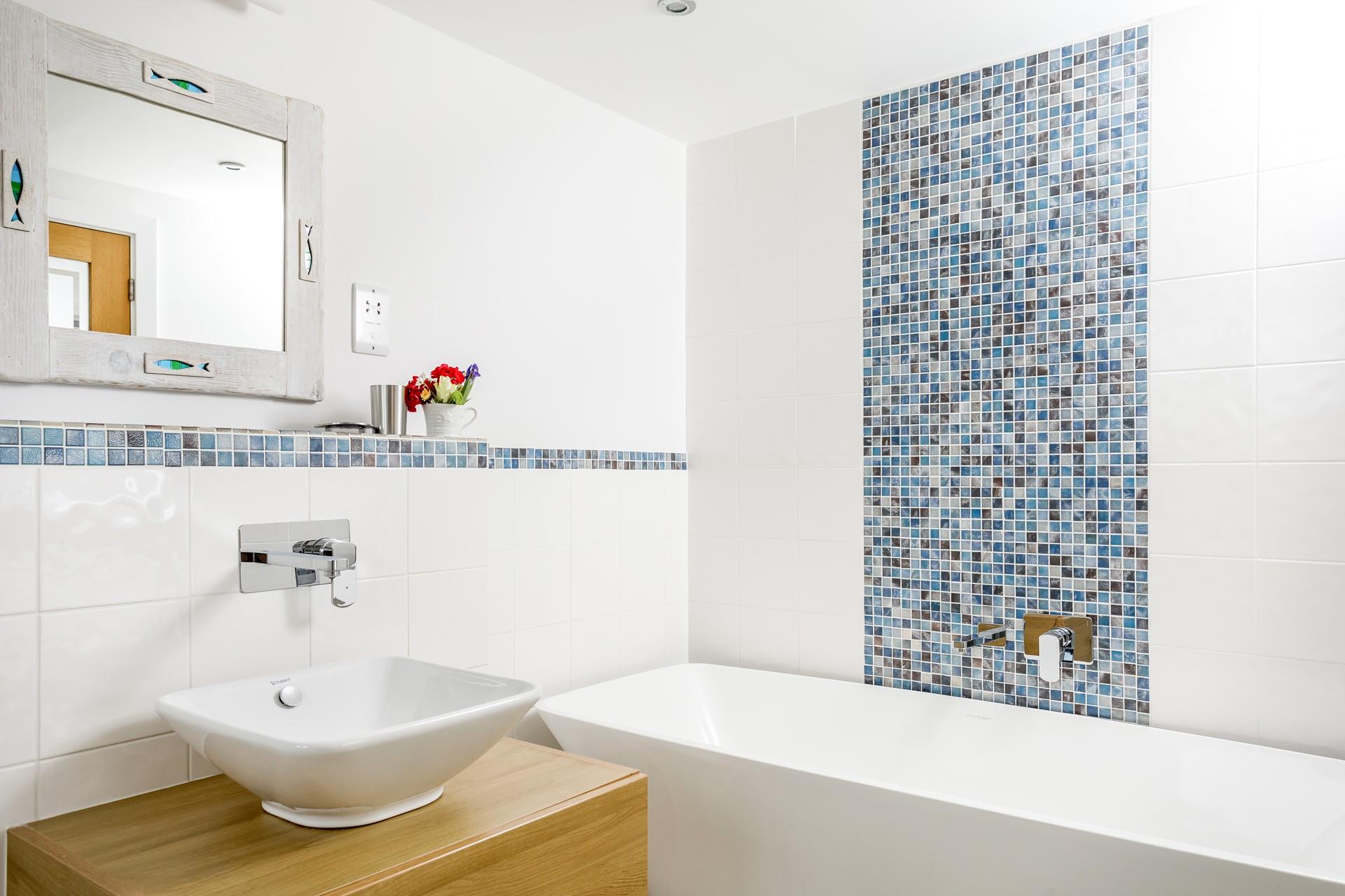 The modern ensuite bathroom has stylish tiles and a bath to relax in.