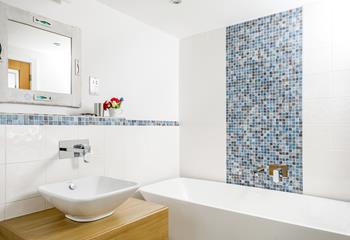 The modern ensuite bathroom has stylish tiles and a bath to relax in.