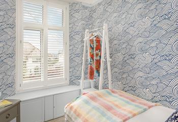 Bedroom 2 has a single bed and wallpaper reflecting the sea's waves.