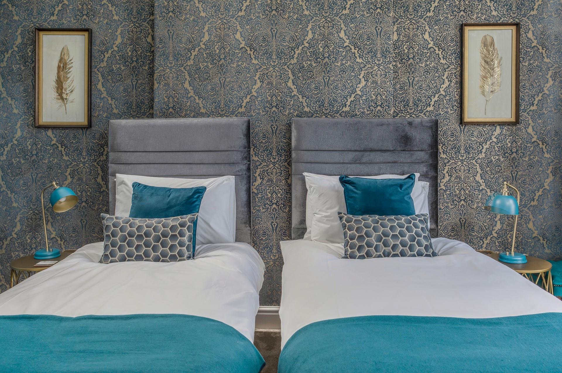 Bright blue decor and luxurious wallpaper make bedroom 1 a gorgeous space to relax.