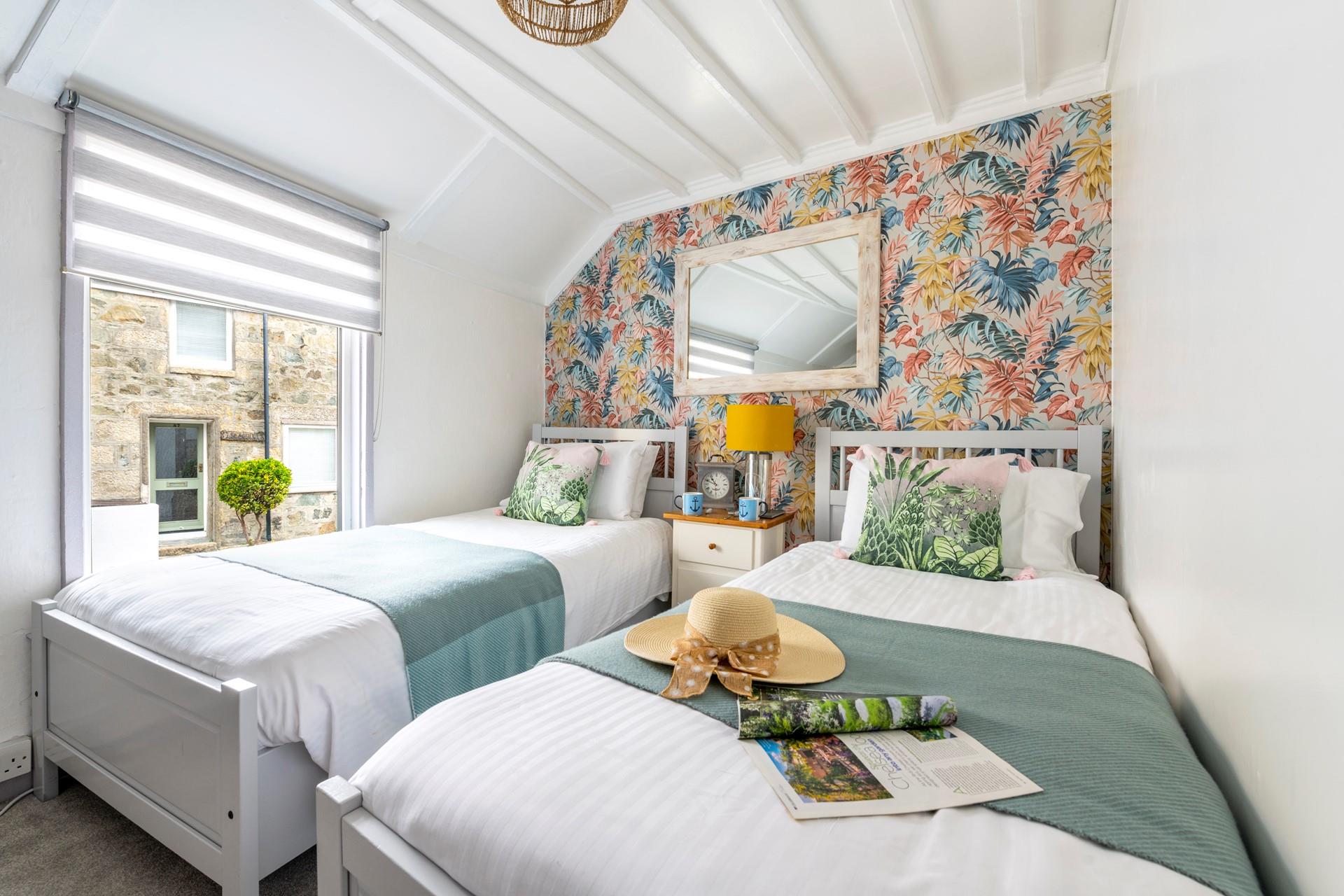 Bedroom 2 has bright wallpaper and lovely green and white interiors.