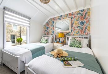 Bedroom 2 has bright wallpaper and lovely green and white interiors.