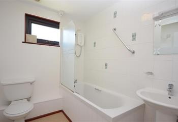 The simple family bathroom has a shower and bath, great for after beach days.