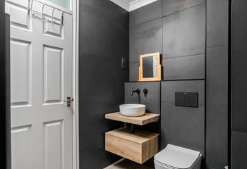 The modern bathroom has black tiles and a stylish sink.