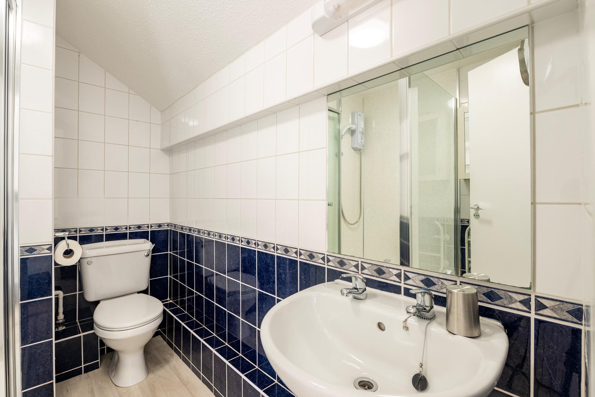 The bathroom has blue and white tiles and is perfectly equipped for getting ready for the day.