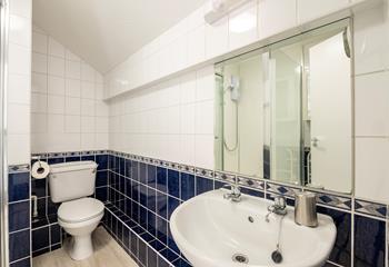 The bathroom has blue and white tiles and is perfectly equipped for getting ready for the day.