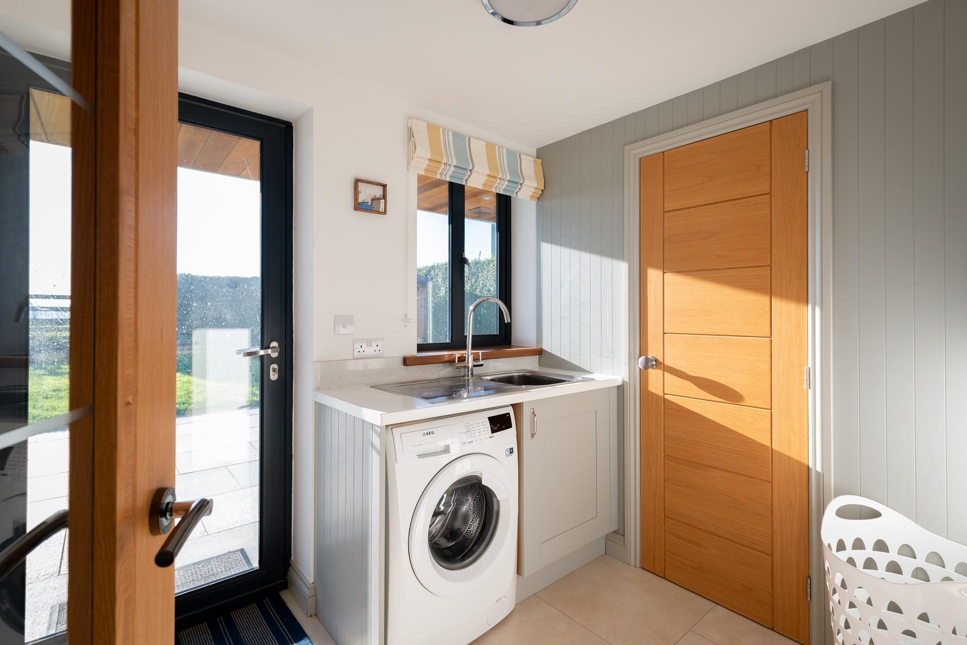 The utility is well-equipped with a washing machine and leads out onto the patio.