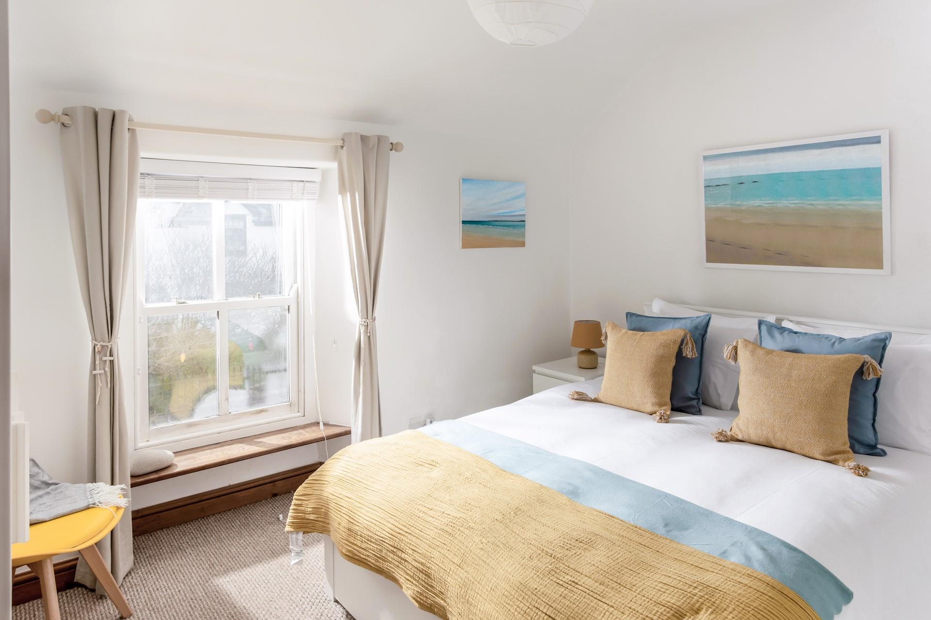 The king size bedroom is decorated with a beach theme featuring lovely artwork.