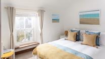 The king size bedroom is decorated with a beach theme featuring lovely artwork.