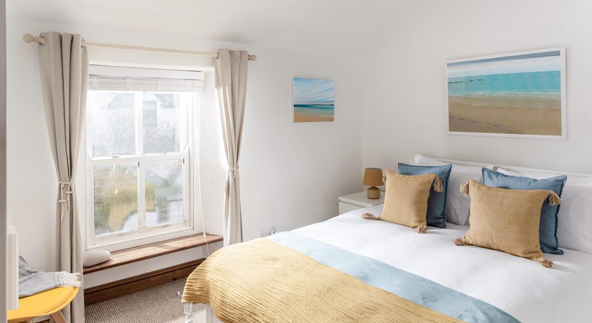 The king size bedroom is decorated with a beach theme featuring lovely artwork.