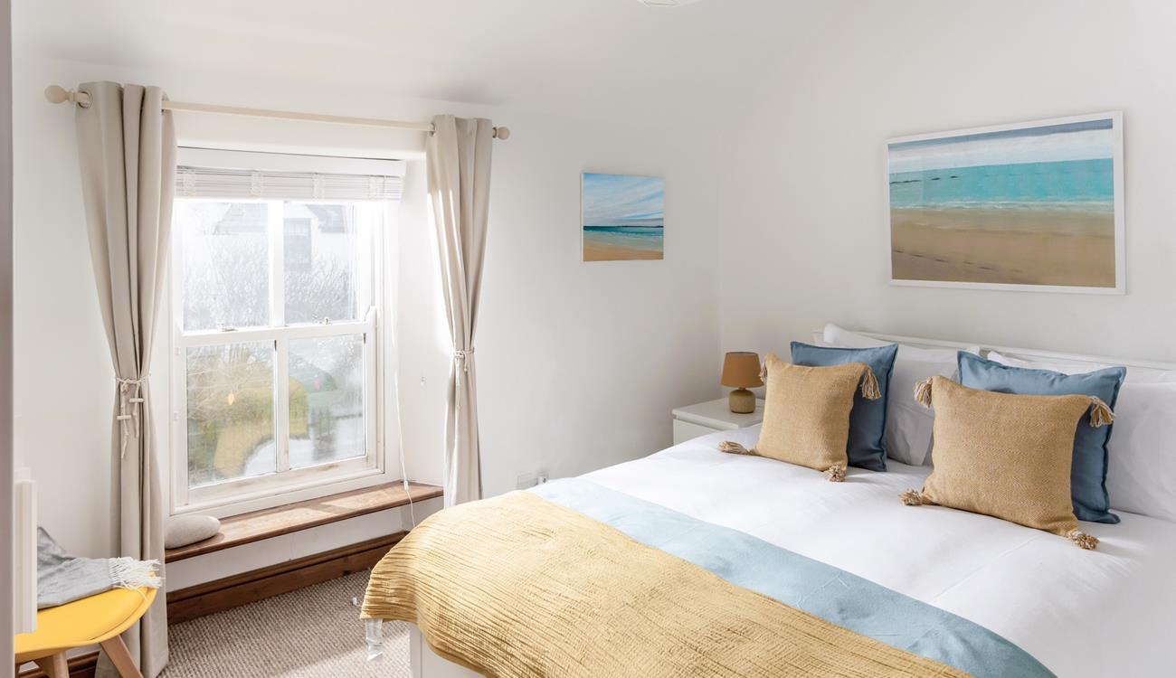 The king size bedroom is decorated with a beach theme featuring lovely artwork.