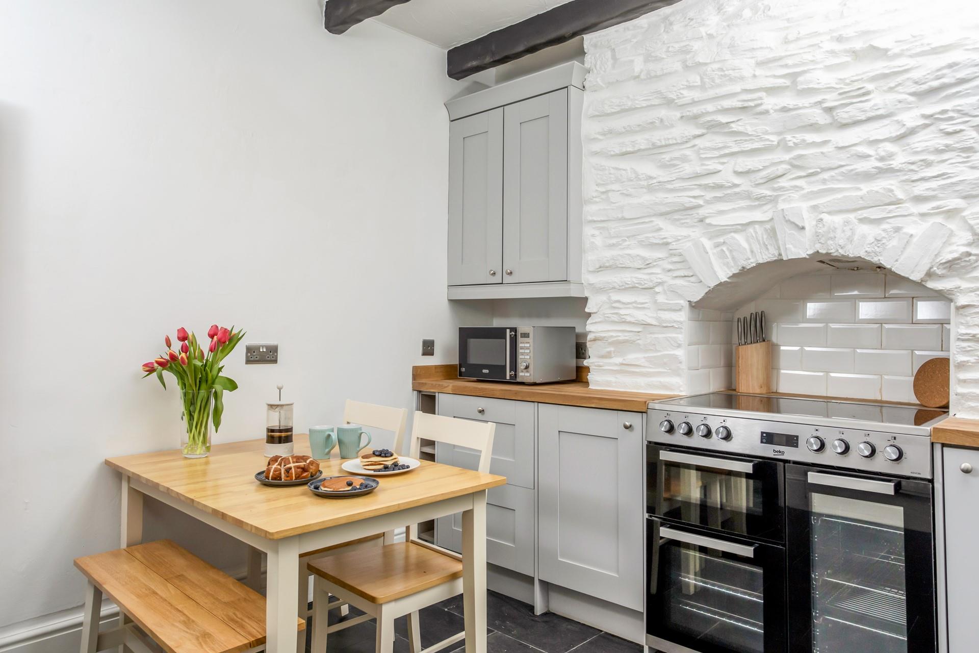 The cottage-style kitchen has traditional exposed beams and original stone.
