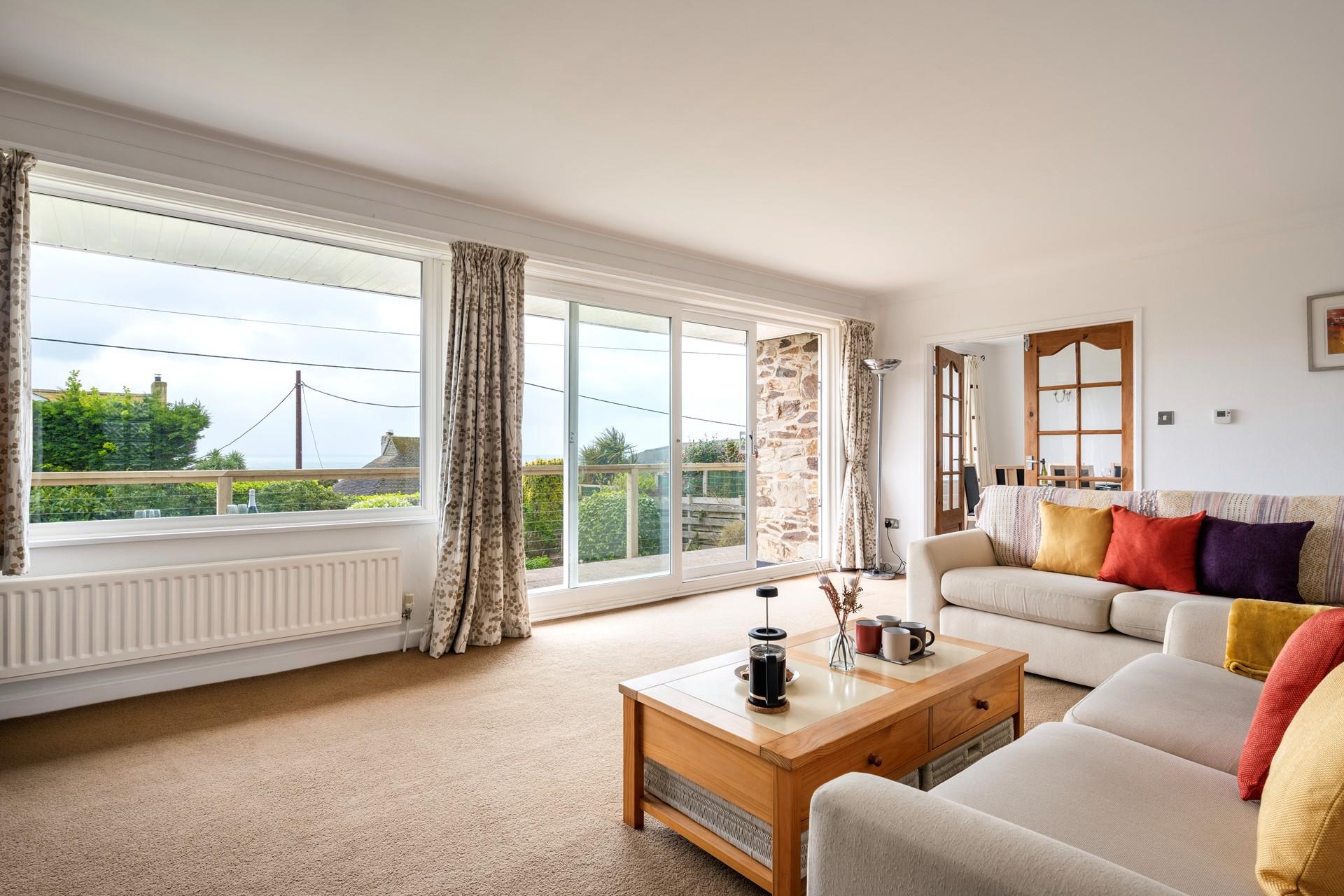 The sitting room is spacious and decorated with bright cushions.