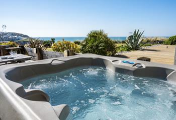 Dip into the bubbling hot tub with the sea view backdrop.