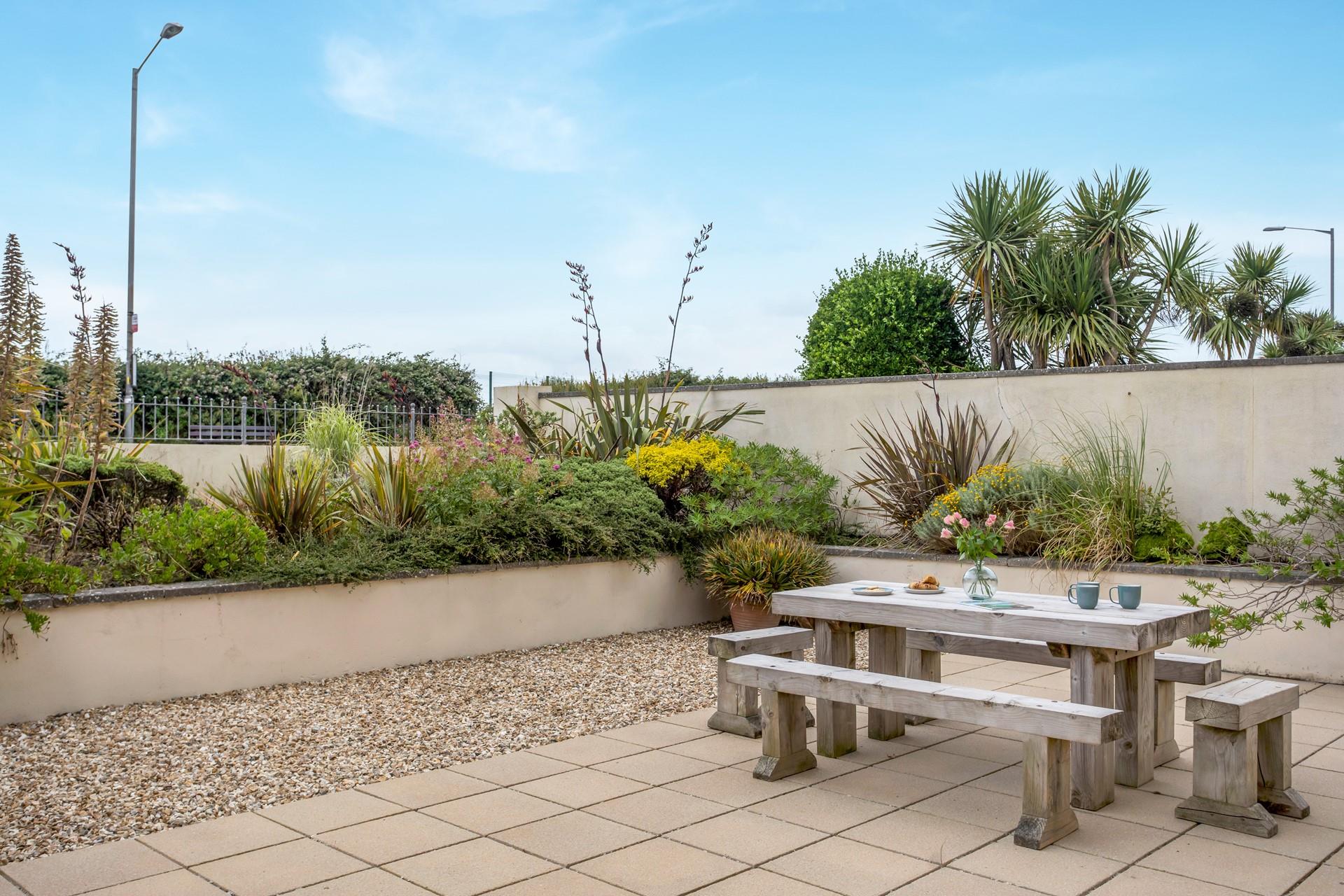 The secluded outdoor space is bordered by lush Cornish greenery.