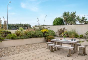 The secluded outdoor space is bordered by lush Cornish greenery.