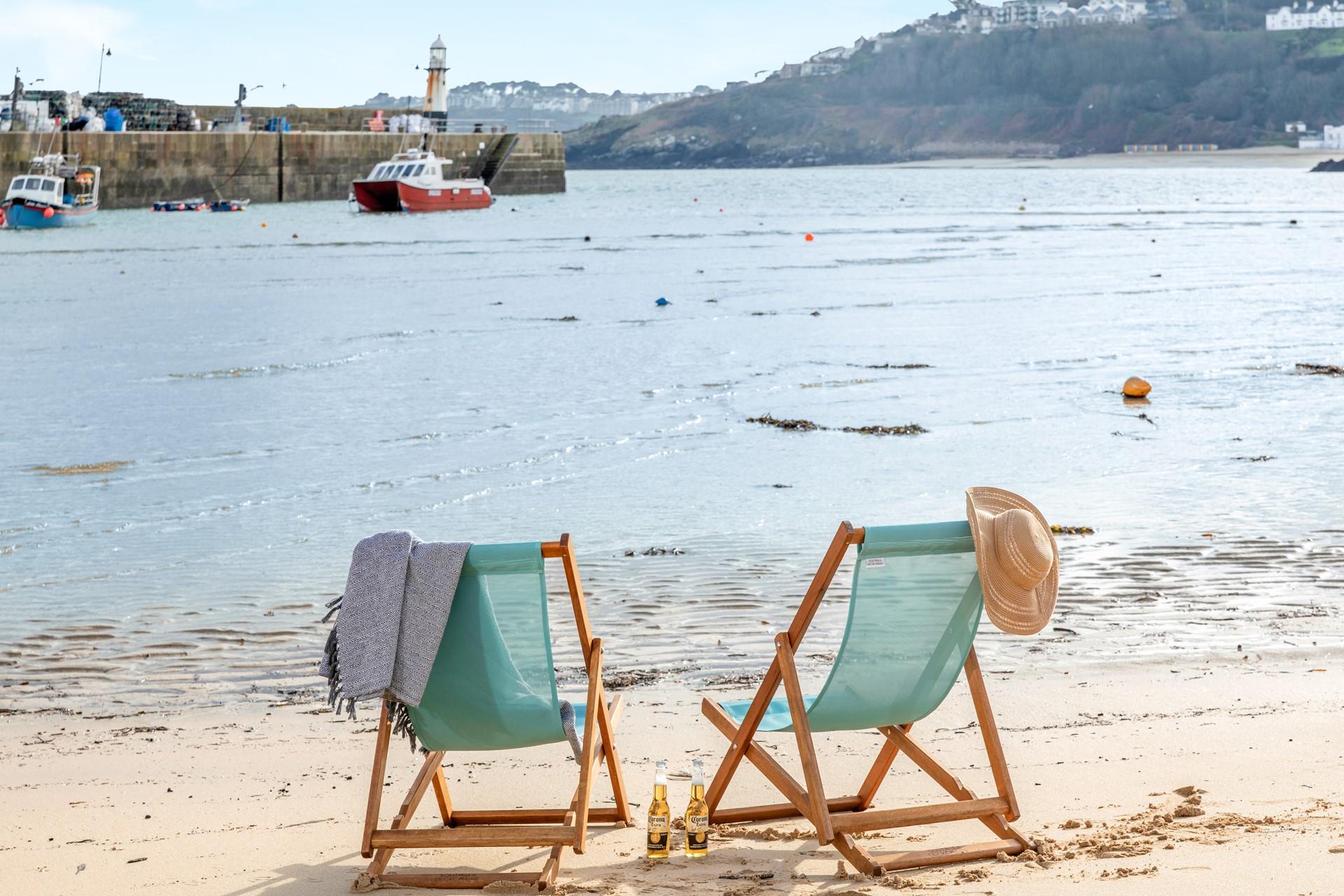 Sit on the beach in a deckchair in the summer sun.