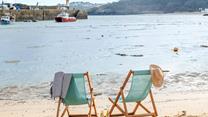 Sit on the beach in a deckchair in the summer sun.