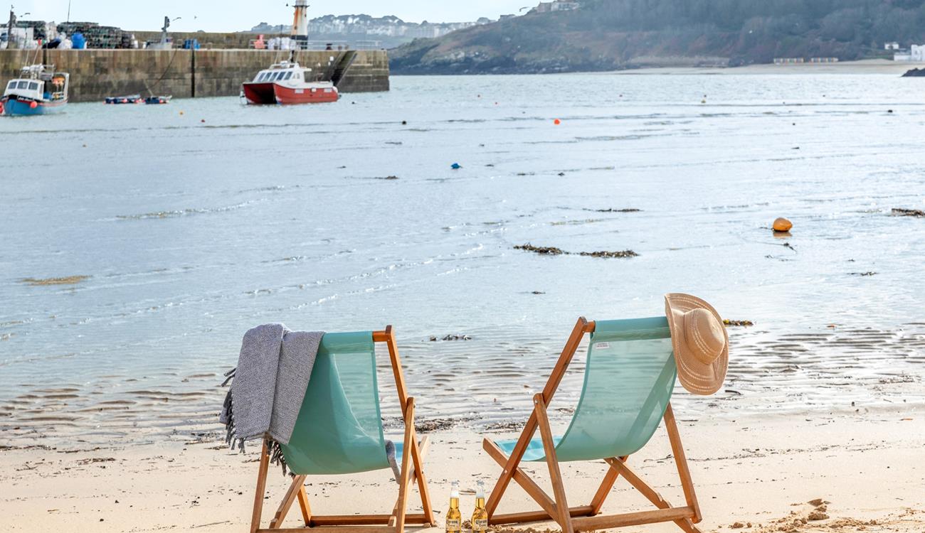 Sit on the beach in a deckchair in the summer sun.