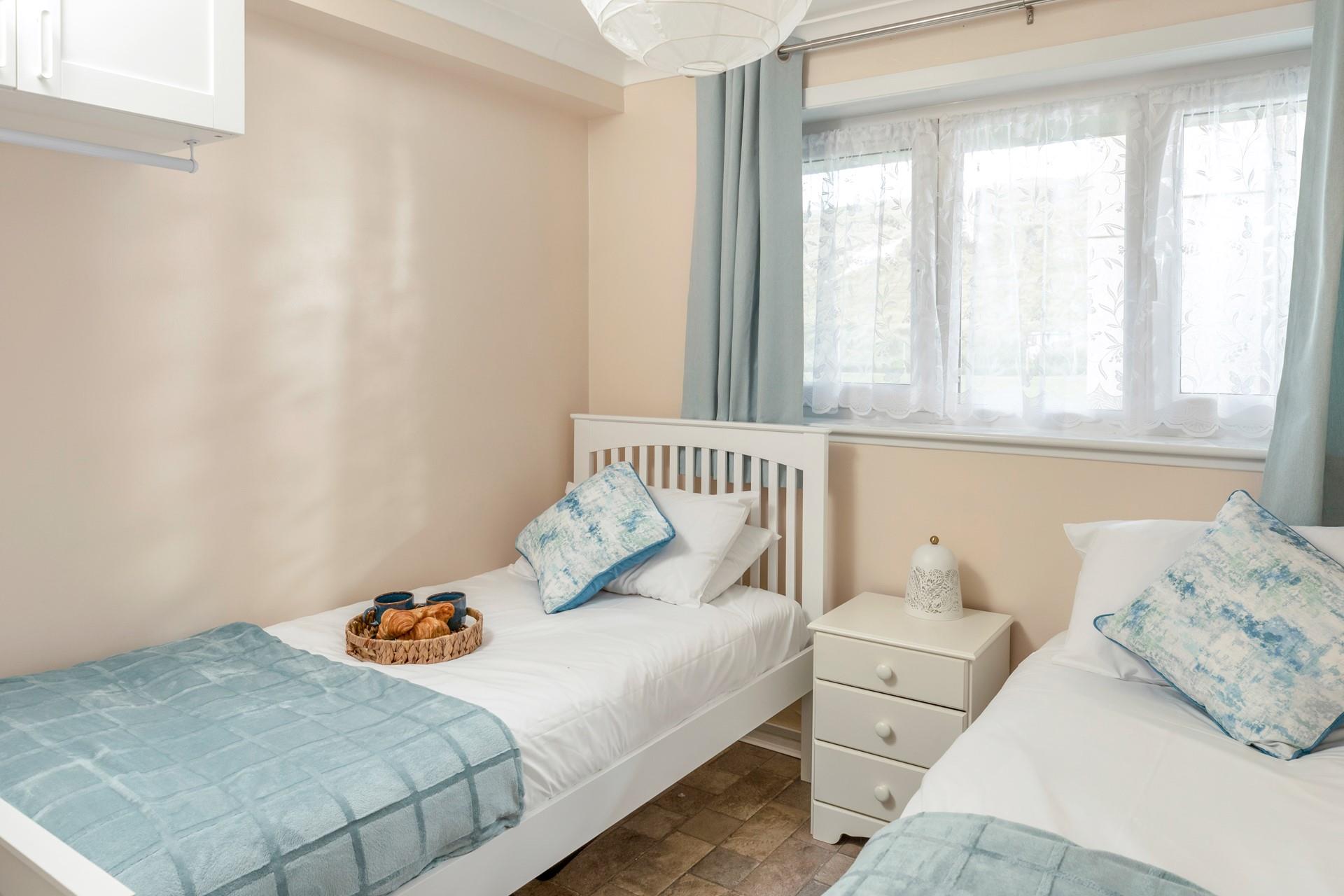 Bedroom 2 has twin beds and is decorated with pastel blues. 