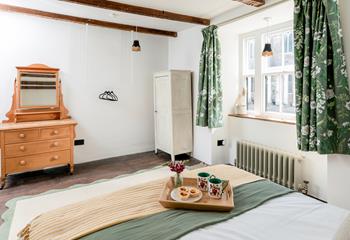 The bedroom is spacious with traditional features such as the beams and furniture.