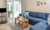 The sitting room has a seaside theme and is decorated with lovely blue-toned cushions. - Thumbnail Image