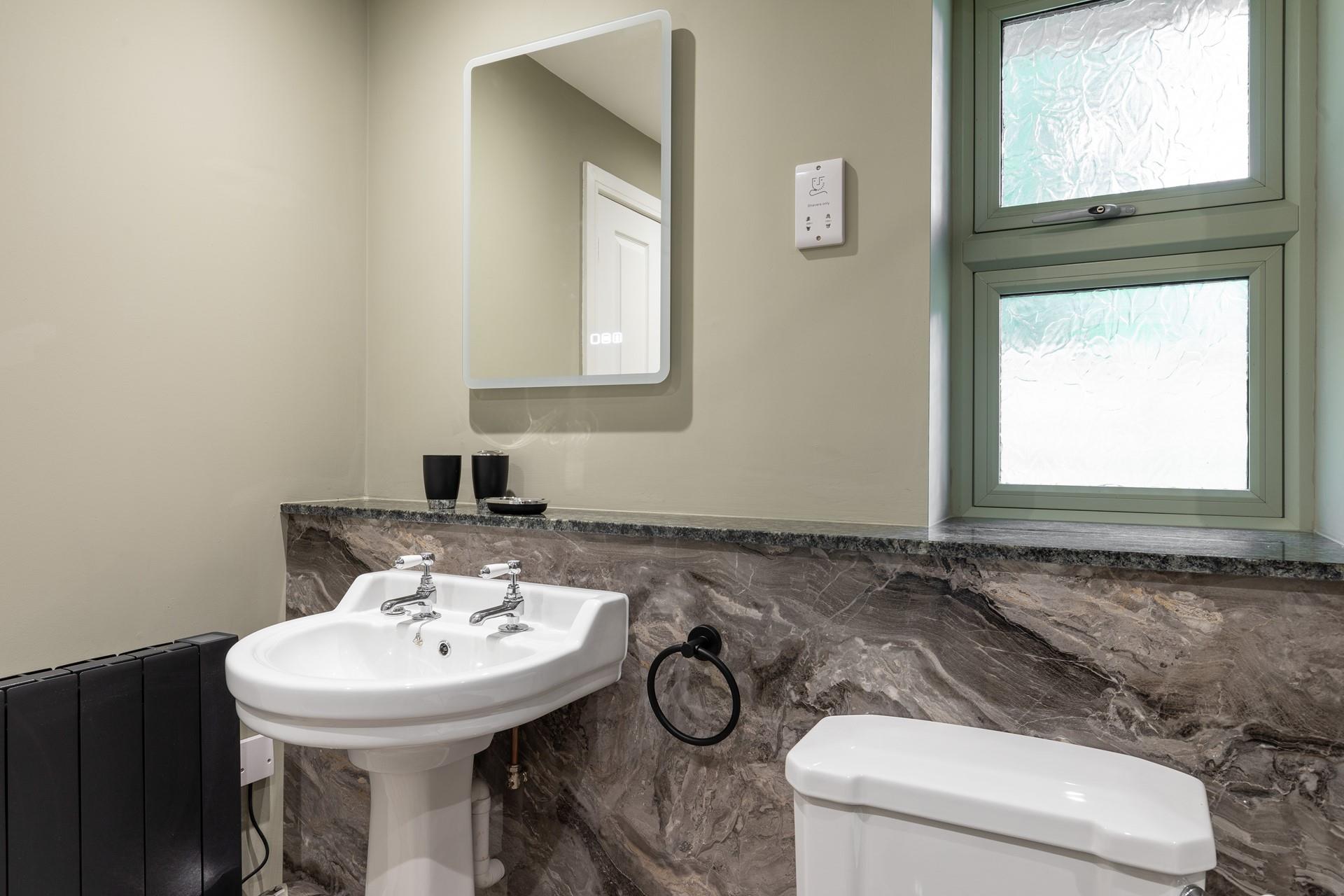 Stylishly decorated in muted tones, the bathroom is spacious and bright.