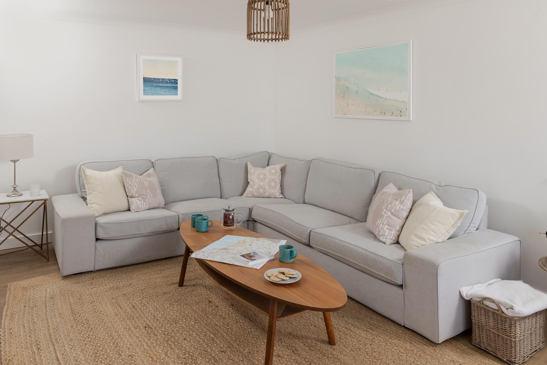 The sitting room offers space to relax and unwind, surrounded by coastal artwork.