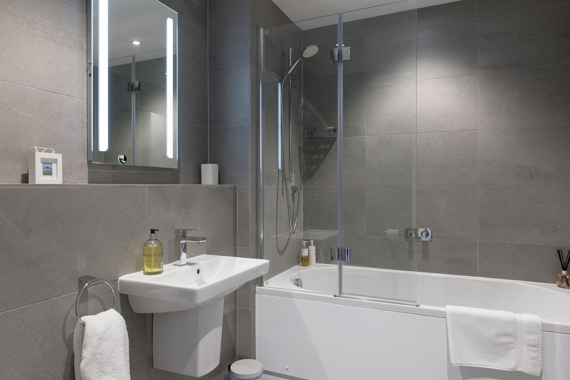 The sleek family bathroom benefits from a bath and shower.