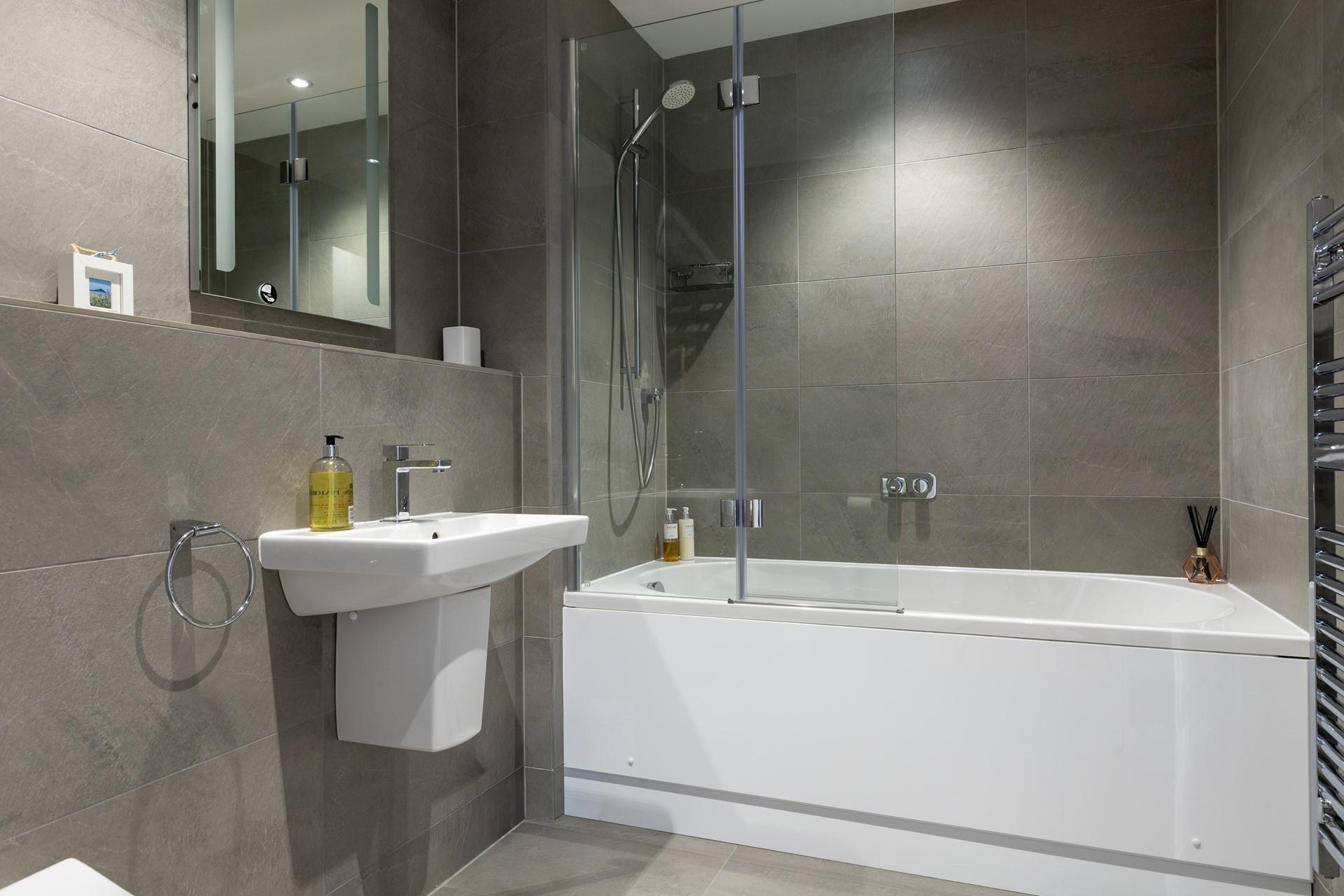 The sleek family bathroom benefits from a bath and shower.