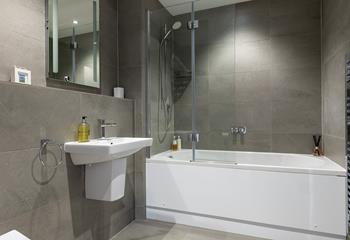 The sleek family bathroom benefits from a bath and shower.