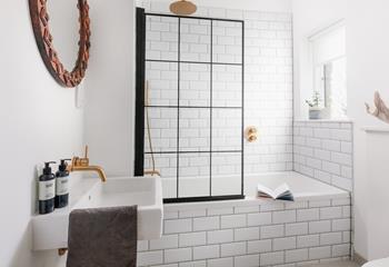 Light and bright, the modern family bathroom has a bath and shower.
