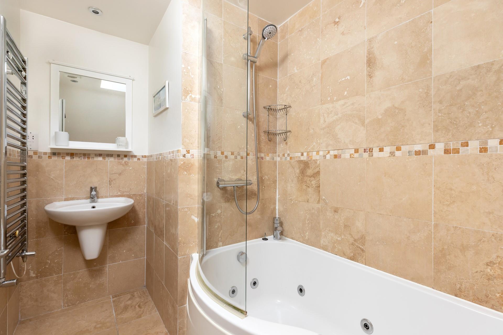 The bathroom features a luxurious jacuzzi bath, perfect after a day of coastal rambling!