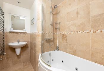 The bathroom features a luxurious jacuzzi bath, perfect after a day of coastal rambling!