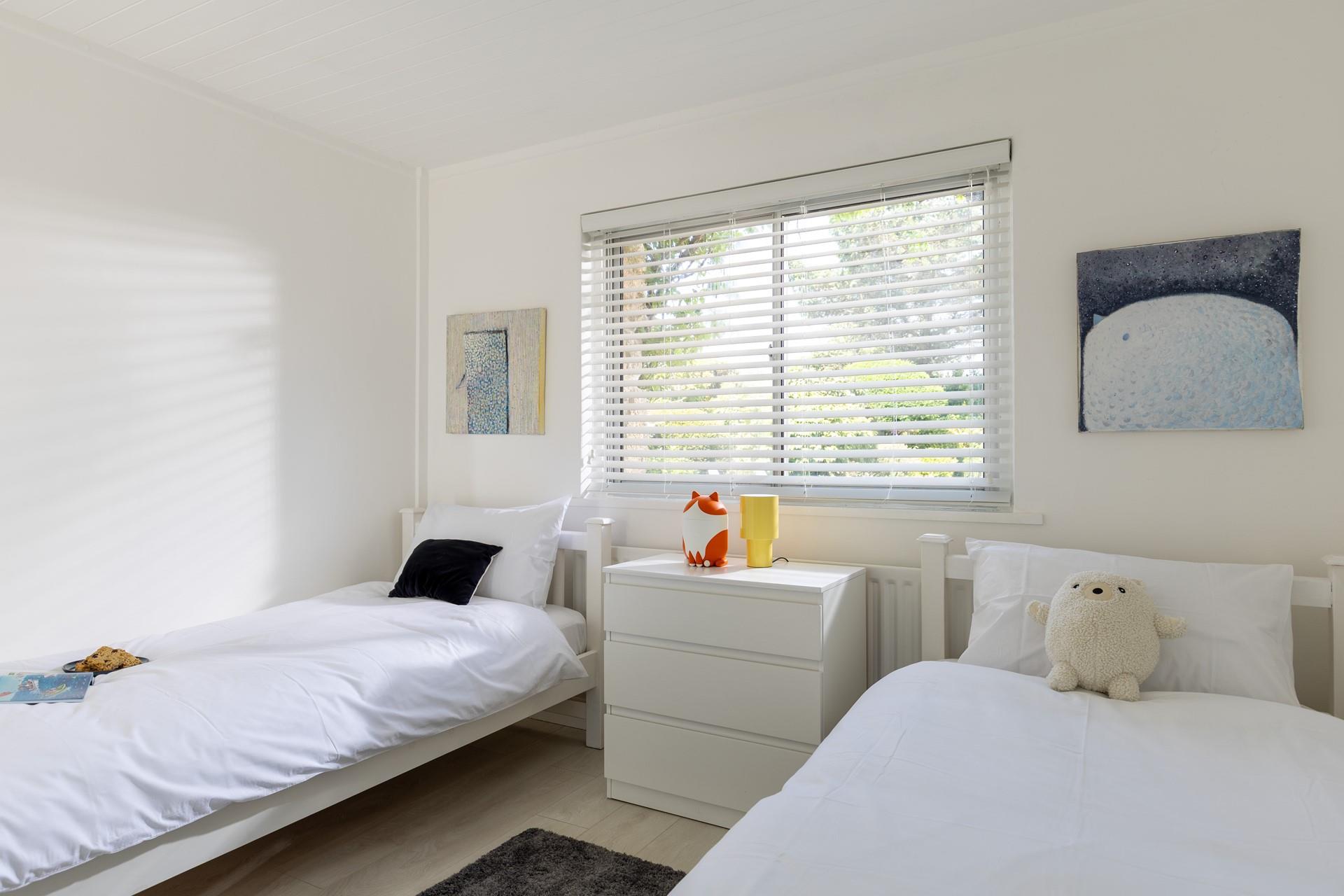Bedroom 2 has twin beds and fun pops of colour.