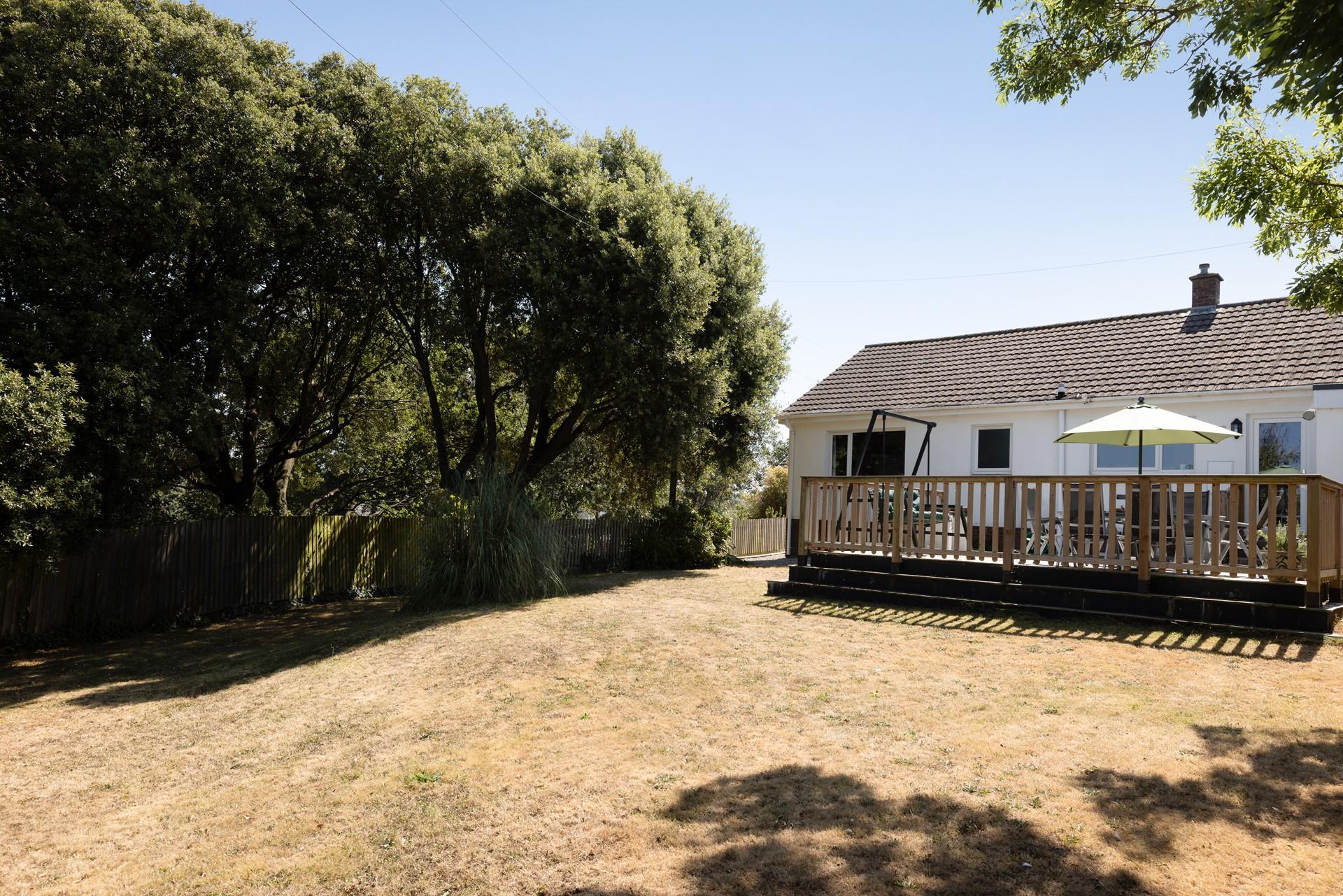 Leafy trees border the sloping lawn, creating an idyllic sheltered garden.