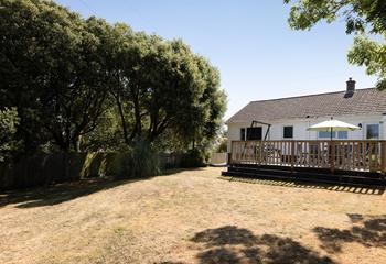 Leafy trees border the sloping lawn, creating an idyllic sheltered garden.
