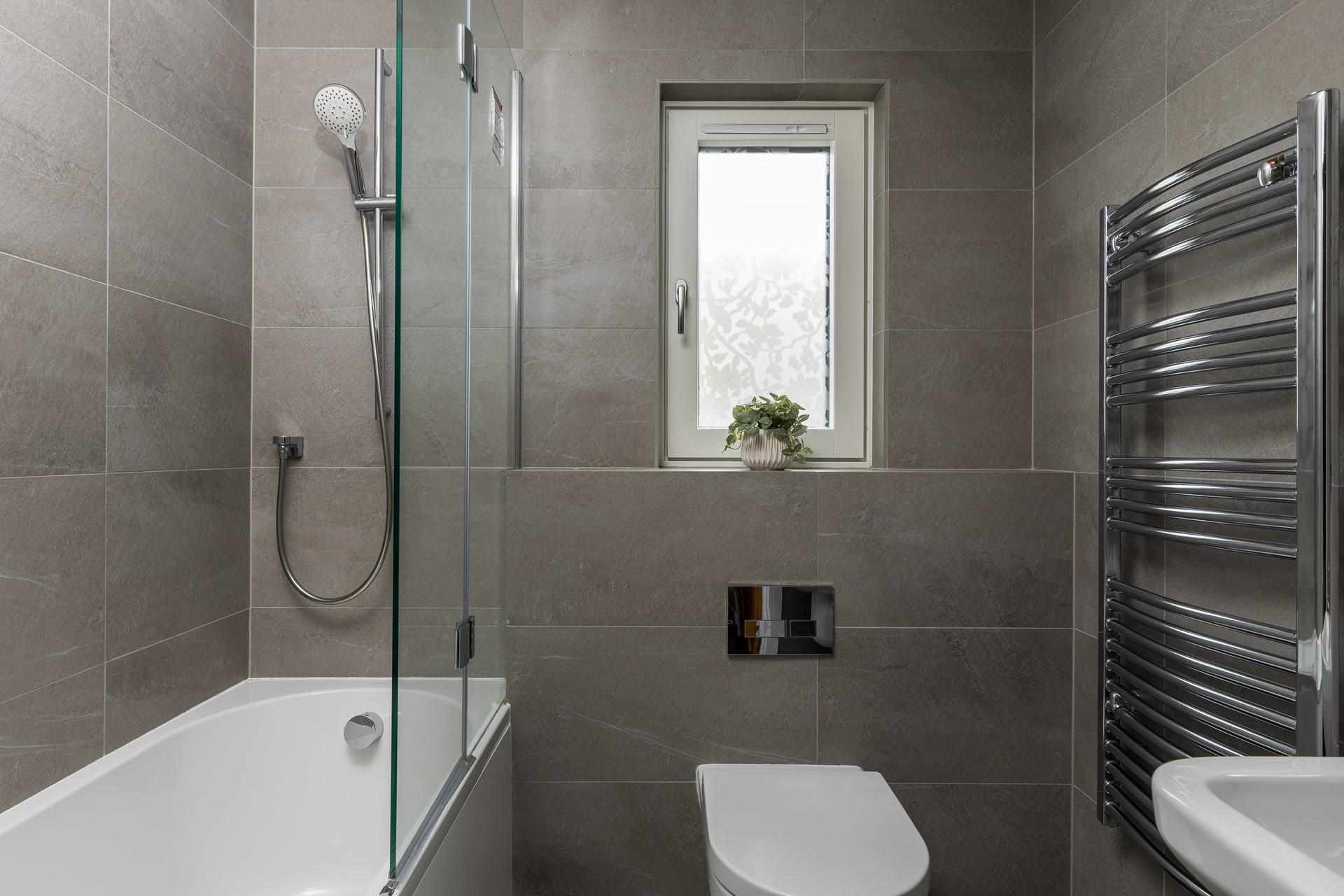 The modern family bathroom has a shower and bath.